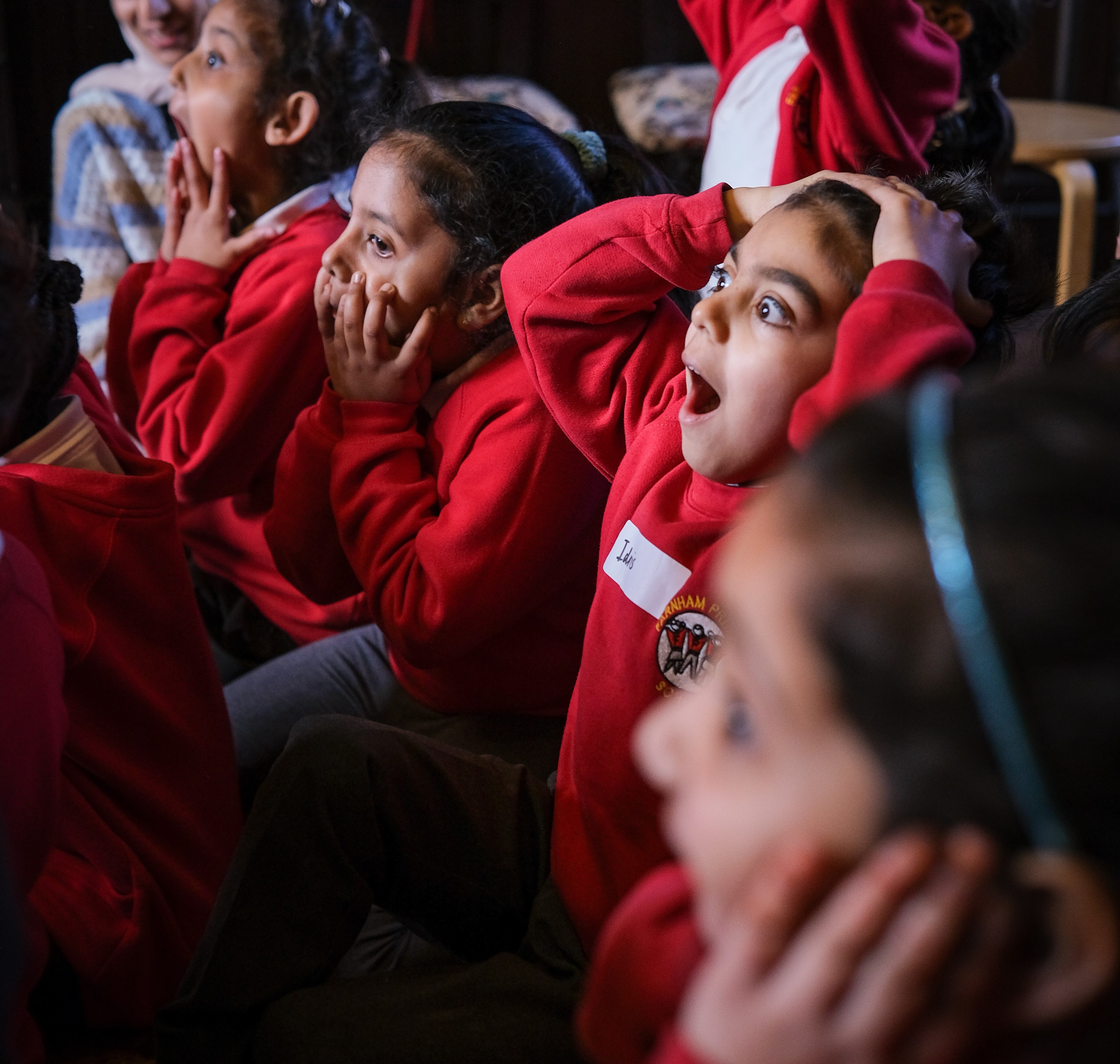 Primary students holding heads in amazement during story time