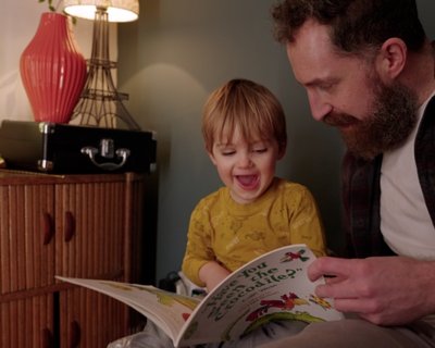 Father and toddler son read a picture book together. Early Words Matter