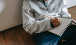Writing in notebook on lap