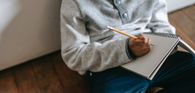 Writing in notebook on lap