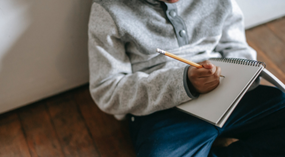 Writing in notebook on lap