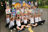 Young pupils holding up books above their heads