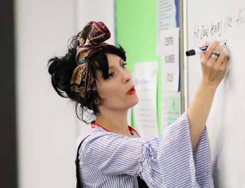 A teacher in a classroom writing on a whiteboard