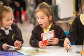 Two primary school children look at books excitedly as part of the Young Readers Programme